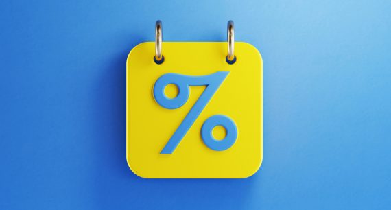 Yellow calendar with blue percentage sign on blue background. Horizontal composition with copy space. Top view.